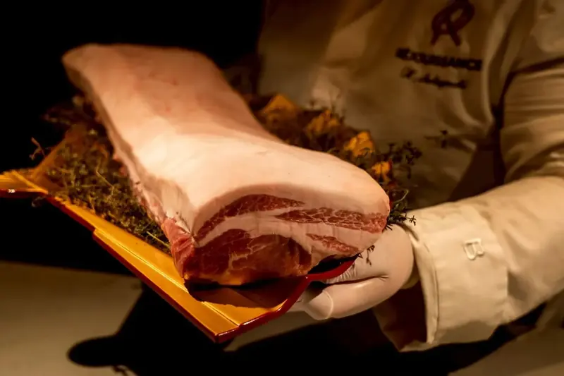 RÉJOUISSANCEの厨房で肉の食材を手にするシェフ